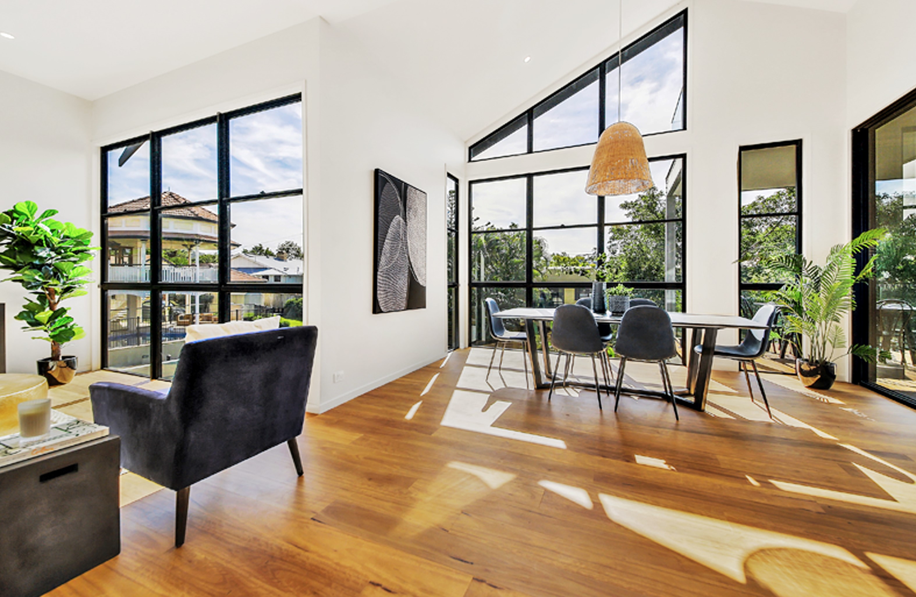 Modern dining area with large double hung windows, dining set table with chairs, and wooden floor. 